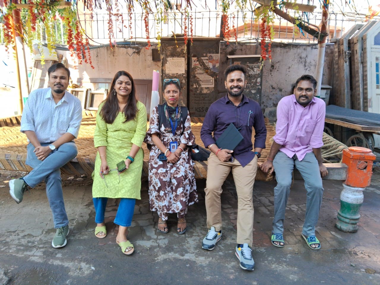Five people in a row smiling at the camera sitting outside in Amritsar