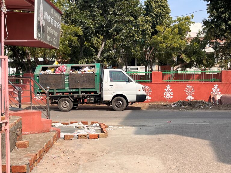 Waste collection vehicle going past a typical pink Jaipur wall
