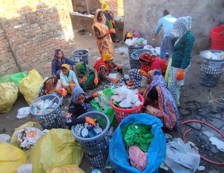 Group of women sorting plastic together on the floor